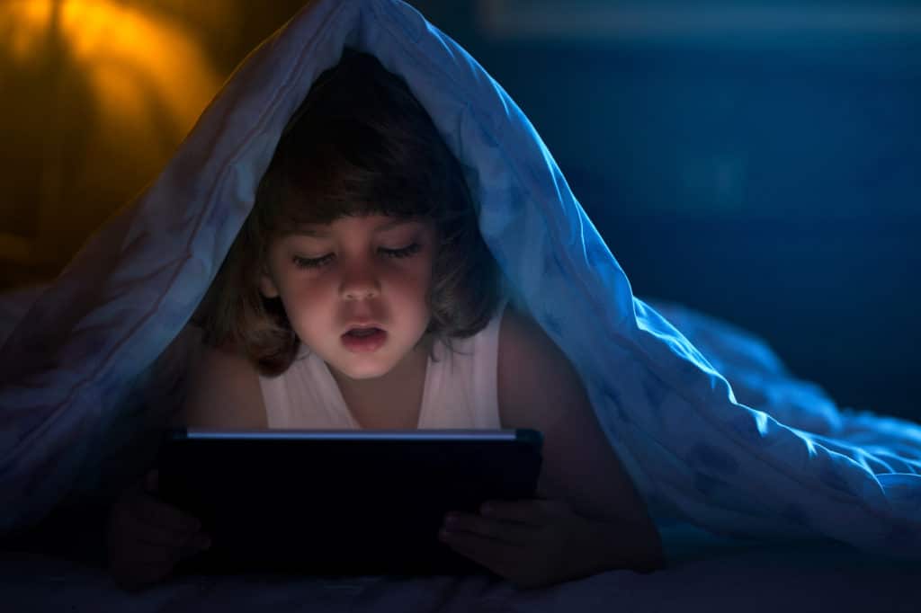 Close up of little boy watching cartoons on the digital tablet at night with copy space