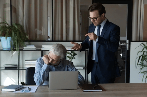Man being reprimanded at work while uncomfortable