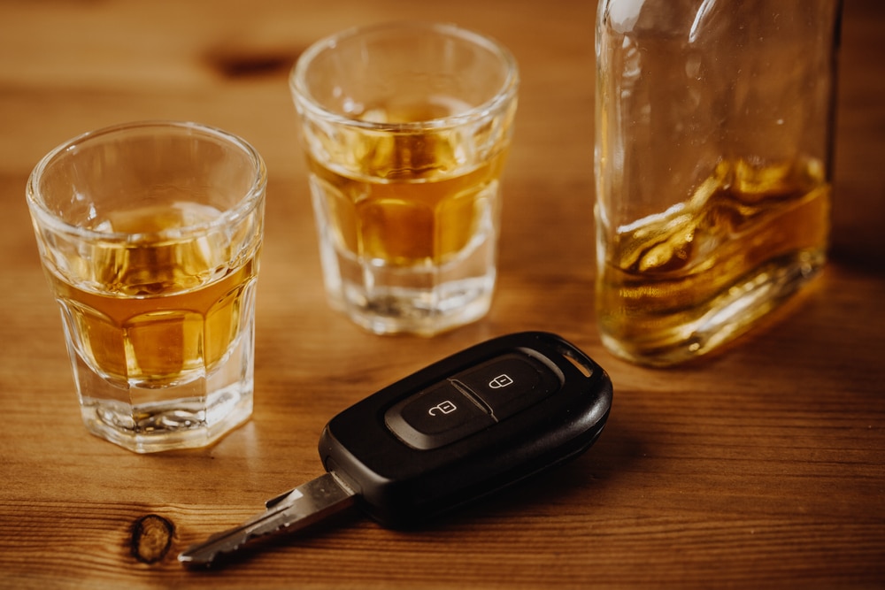Keys beside shot glasses full of alcohol. Drunk driving can seriously injure other parties, so please drive sober.